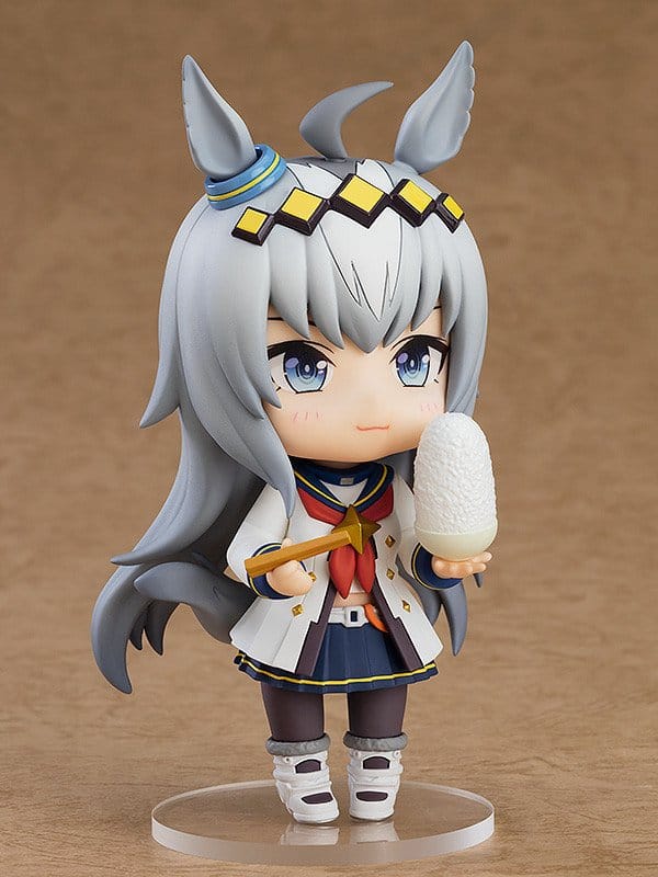 Anime character figurine with gray hair and blue eyes holding a white object on a brown background