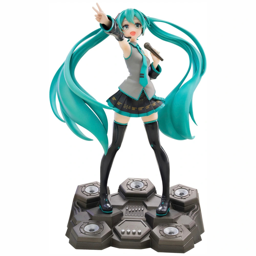 A collectible figurine of Hatsune Miku standing on a dark gray speaker-like base, with long turquoise twin-tails, a gray top, black skirt, and thigh-high black boots against a plain white background.