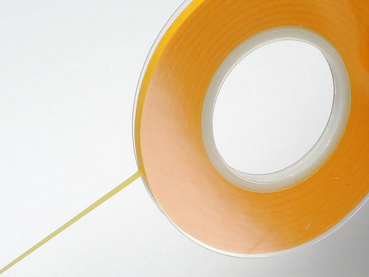 Close-up of a roll of orange tape on a white background