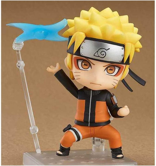 A chibi-style Naruto figurine with spiky yellow hair, an orange and black jumpsuit, and a silver headband, posed on a clear display stand with a blue energy effect accessory against a plain tan background.