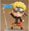 A chibi-style Naruto figurine with spiky yellow hair, an orange and black jumpsuit, and a silver headband, posed on a clear display stand with a blue energy effect accessory against a plain tan background.