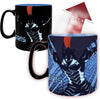 A color-changing ceramic mug featuring a graphic of the character Gris from Attack on Titan. The mug is shown in two states: a black mug with a blue interior and a blue mug with a black handle and a red heat-arrow graphic indicating its temperature-changing property.