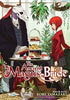 Front cover of the manga book 'The Ancient Magus Bride Volume 1' by Kore Yamazaki, featuring an illustration of a red-haired woman in a red dress standing next to a table with tea and pastries, and a white skeletal figure in a black robe on the left.