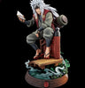 A detailed collectible figurine of the anime character Jiraiya from Naruto, depicted sitting on a wooden platform and holding a book. The figure is set against a solid black background.