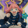 A collectible anime figurine of Anya Forger from My Hero Academia, wearing her signature blue winter coat and pink hair, posed sitting down with a star-shaped accessory.