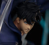 Close-up of an anime-style male character with spiky black hair, blue eyes, and a dark blue hooded outfit against a dark blurred background.