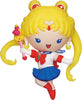 Toy figure of Sailor Moon with yellow hair and a wand on a white background
