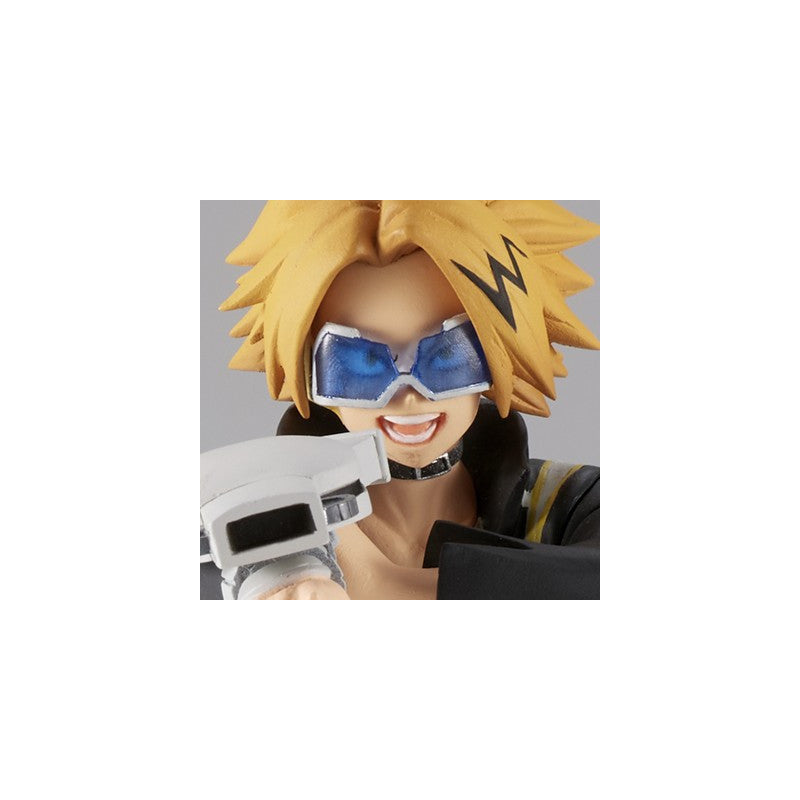 A close-up of a collectible anime figure with spiky blond hair, blue goggles, and a black-and-gold outfit, holding a white device against a light gray background.