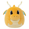 Plush toy resembling a dragon with a yellow body and black eyes on a white background